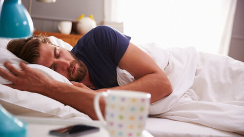 male-sleeping-with-cup-in-forefront
